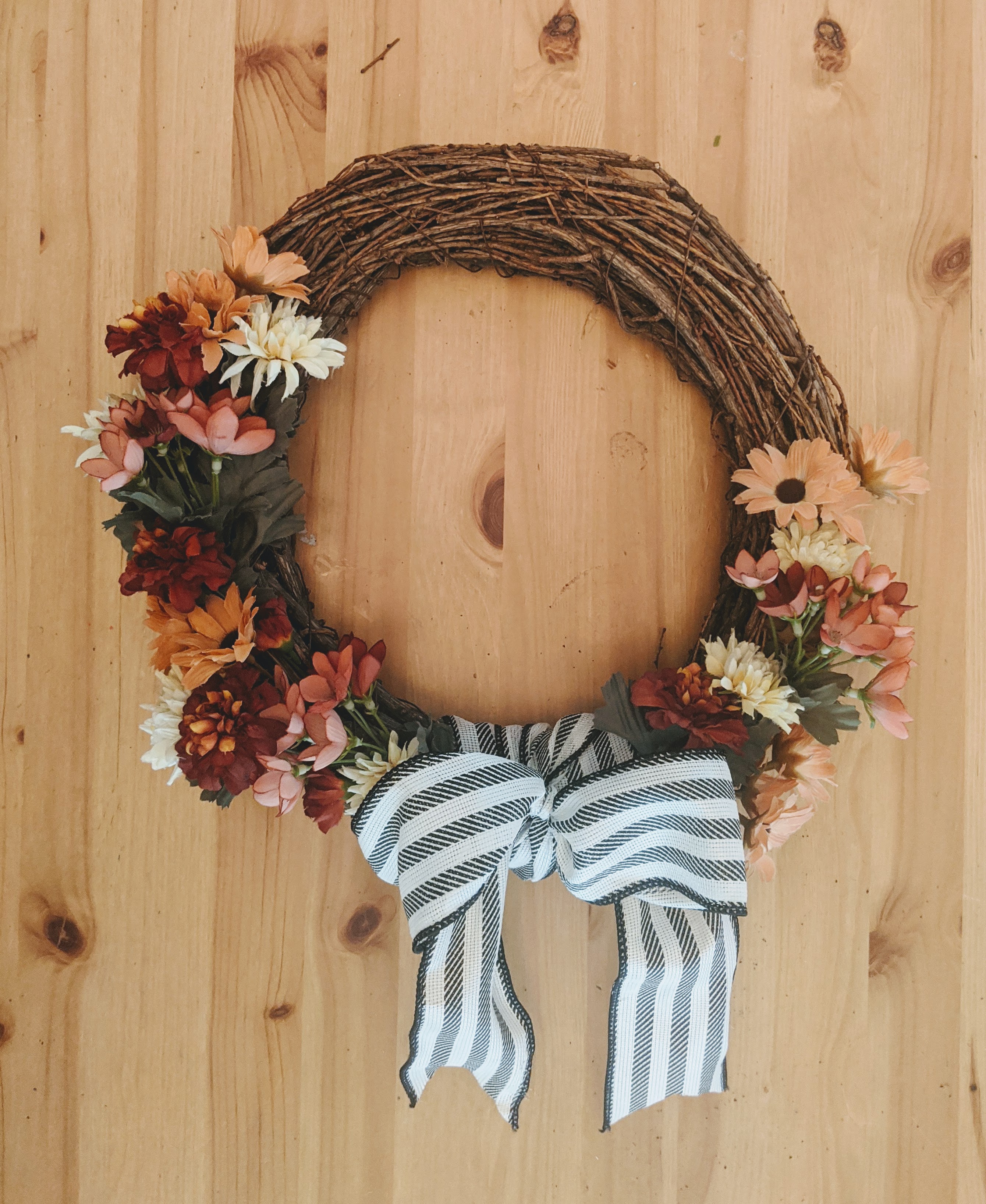 fall wreath made of twigs and vintage flowers with striped bow